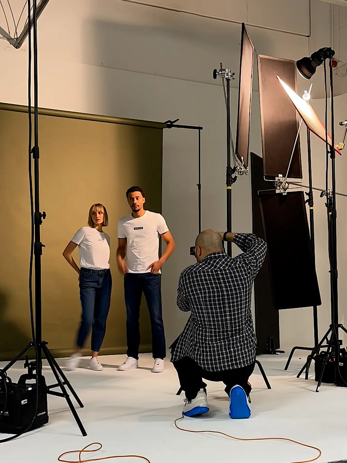 Photographer taking photos from a man and woman. Subjects are wearing white T-short and blue jeans